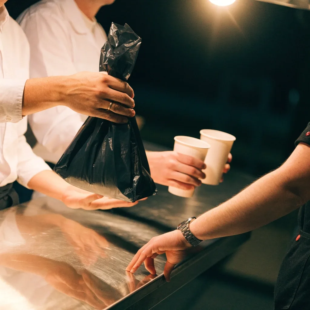 Hand collecting a paper bag from a pickup shelf
